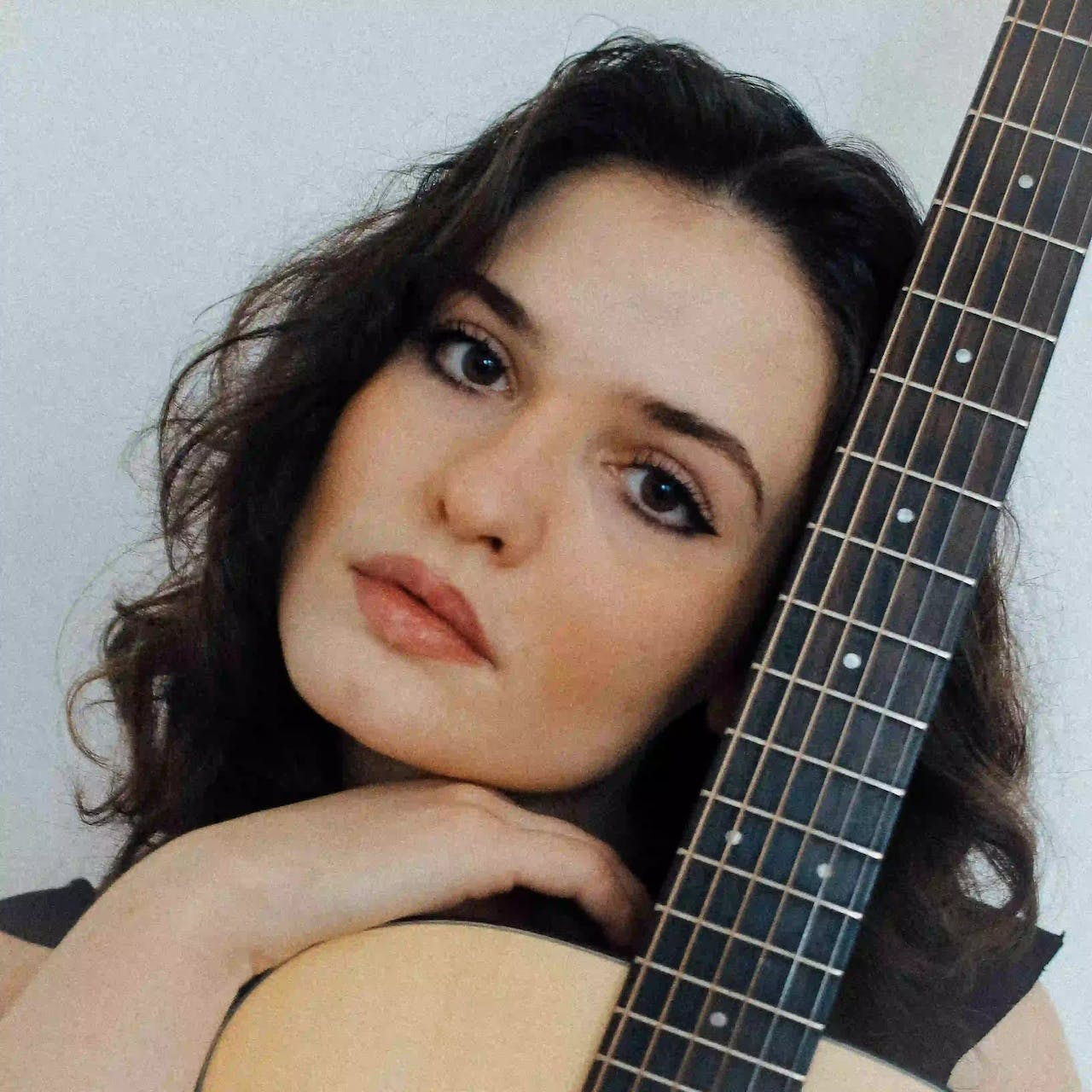 Female singer/songwriter, Violetta Zironi, posing elegantly with her acoustic guitar.